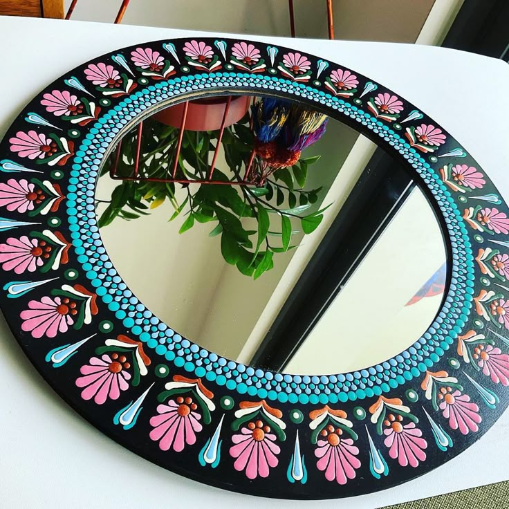 a round mirror sitting on top of a table next to a potted plant in a vase