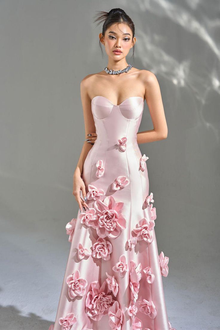 Indulge in a sense of exquisite luxury as you slip into the Samara 3D Floral Strapless Maxi Dress. Handmade from opulent taffeta satin, this breathtaking dress boasts a sweetheart neckline, intricate floral appliques, and an elegant asymmetrical silhouette. Complete with a lace-up back, it is the perfect choice for any formal event or special occasion. Handmade-To-Order. Satin. Unlined. Runs true to size. Hand Wash Cold. Do Not Bleach. Line Dry. Iron Low Heat. ** This dress is Made-To-Order. Whether you choose a standard size or custom measurements, each dress is uniquely handmade by our master tailors to order. Product color may vary due to lighting on images and screen resolution. * For Custom Size - Once you successfully placed an order, please reply to the order confirmation email with Pink Flower Gown, Fancy Stage Outfits, Pink Gown Princesses, Pink Dresses Aesthetic, Luxury Dress Aesthetic, Formal Spring Dresses, High Fashion Prom Dresses, Fairytale Dress Princesses Ball Gowns, Prom Dresses With Flowers