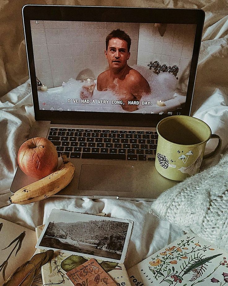 an open laptop computer sitting on top of a bed next to pictures and other items