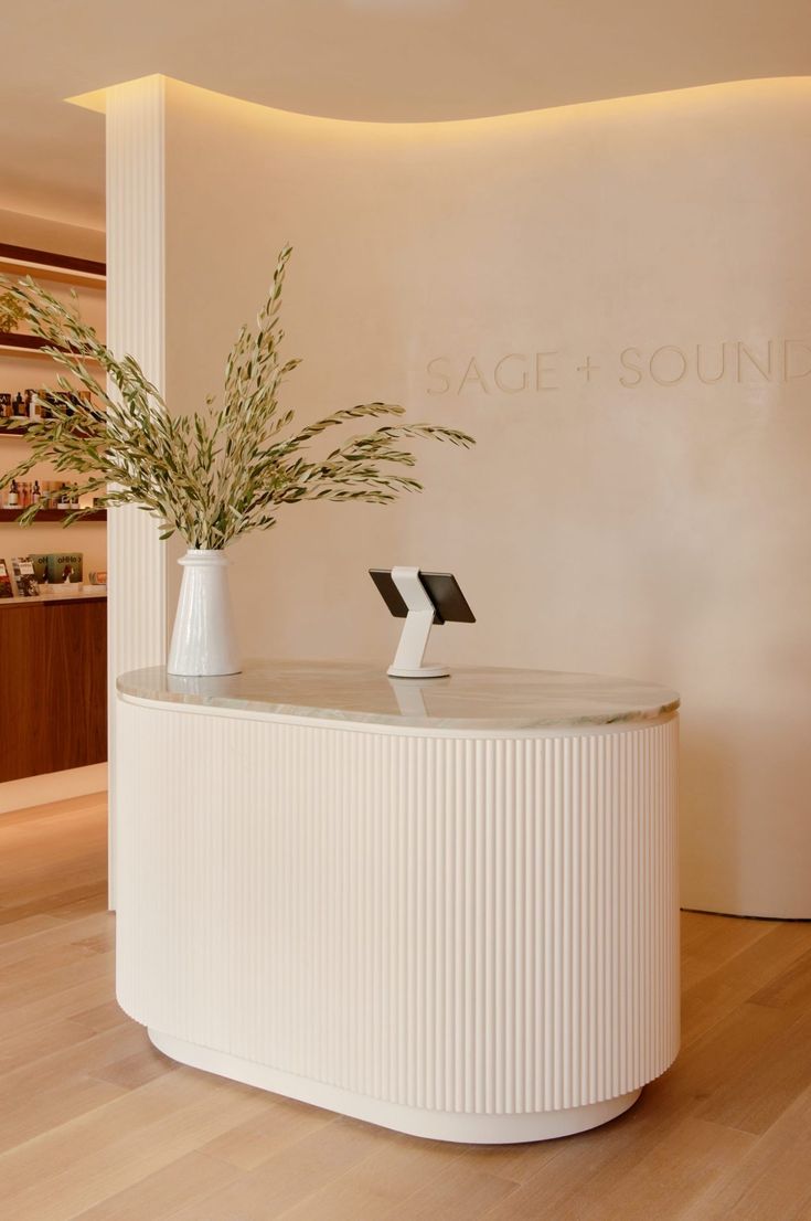 a white reception table with two vases on it and a plant in the middle