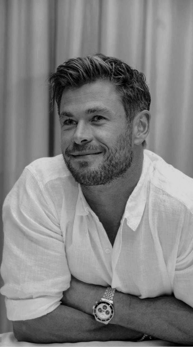 a black and white photo of a man with his arms crossed smiling at the camera