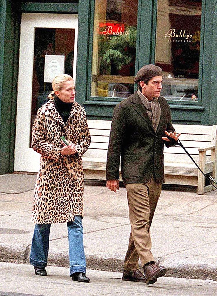 a man and woman walking their dog down the street