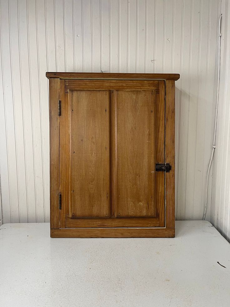 a wooden cabinet sitting in the corner of a room with white walls and flooring