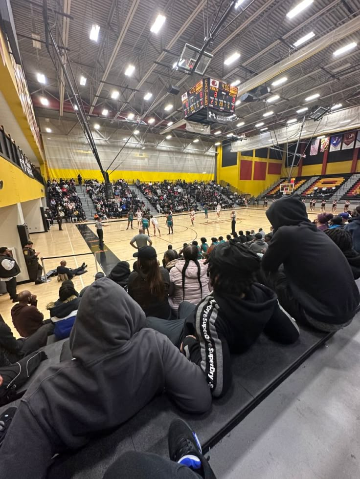 people sitting on the floor watching a basketball game