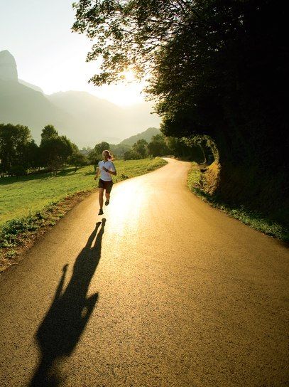 a person running down a road with the sun shining on them