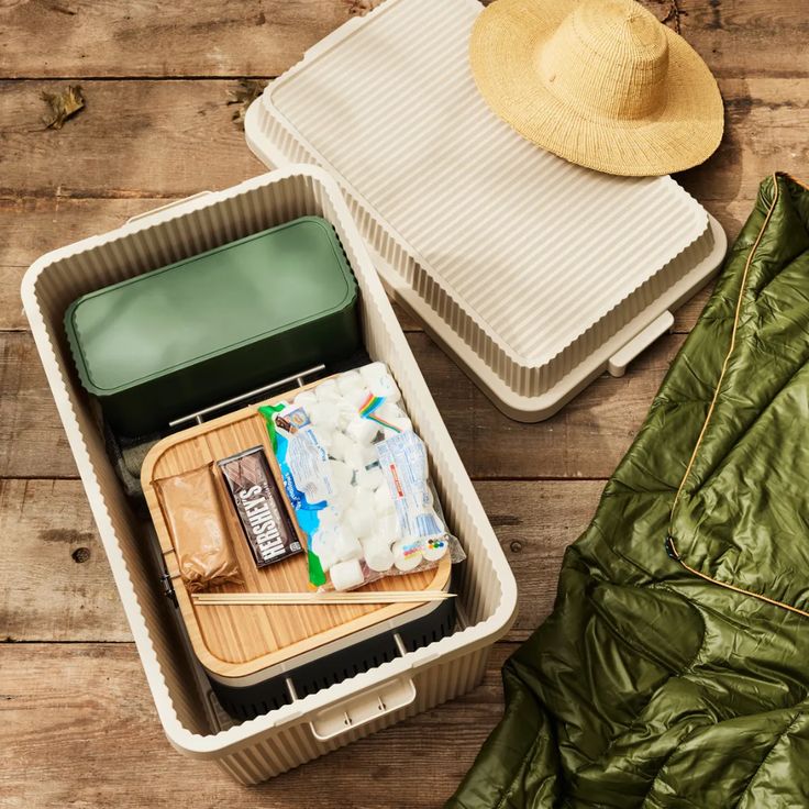 an open suitcase sitting on top of a wooden floor next to a hat and jacket