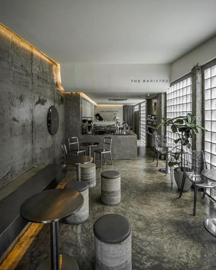 an empty restaurant with tables and stools in the center, along with large windows