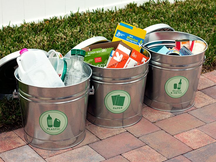 three metal trash cans sitting on top of a brick sidewalk