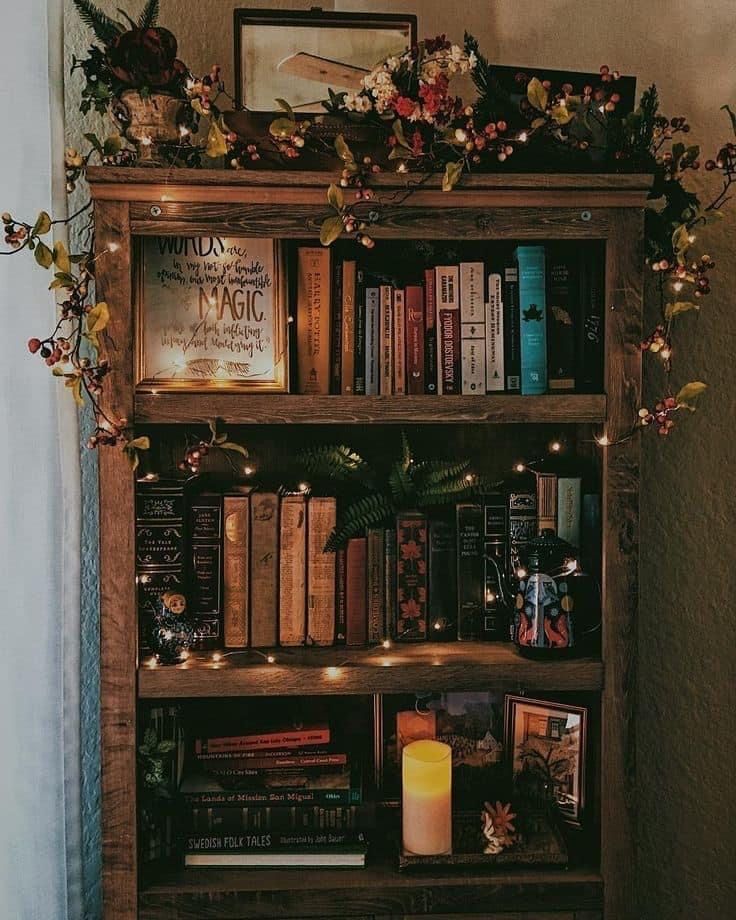 a bookshelf filled with lots of books next to a wall covered in lights