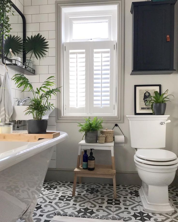 a white toilet sitting next to a bath tub in a bathroom with black and white tiles