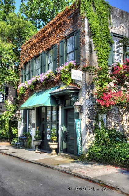 an image of a building with flowers on the outside and green awnings over it