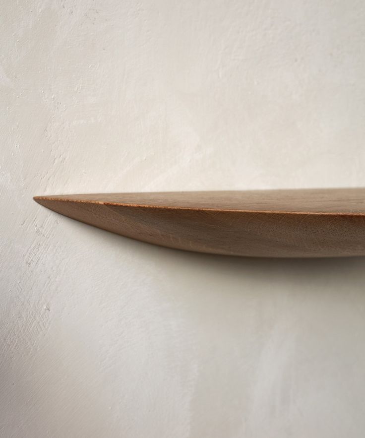 a wooden shelf on the wall with white walls in the background and light colored paint