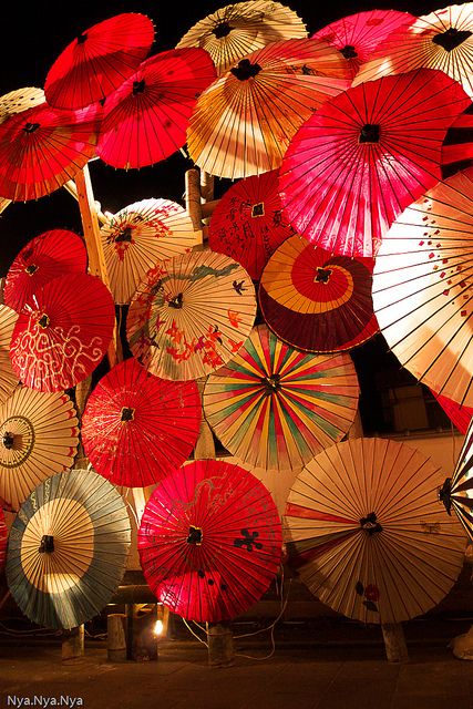 many colorful umbrellas are lit up in the dark