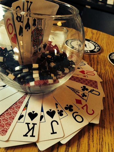 a glass bowl filled with playing cards on top of a wooden table