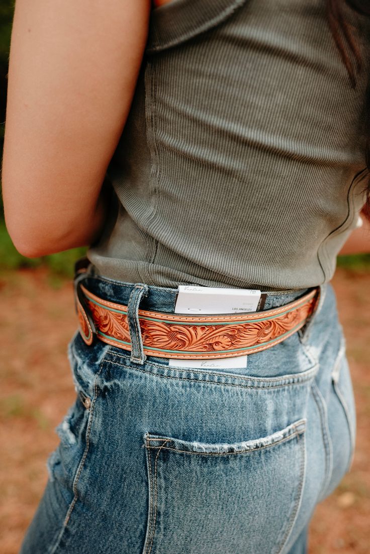 a woman wearing jeans and a belt with a cell phone in her pocket