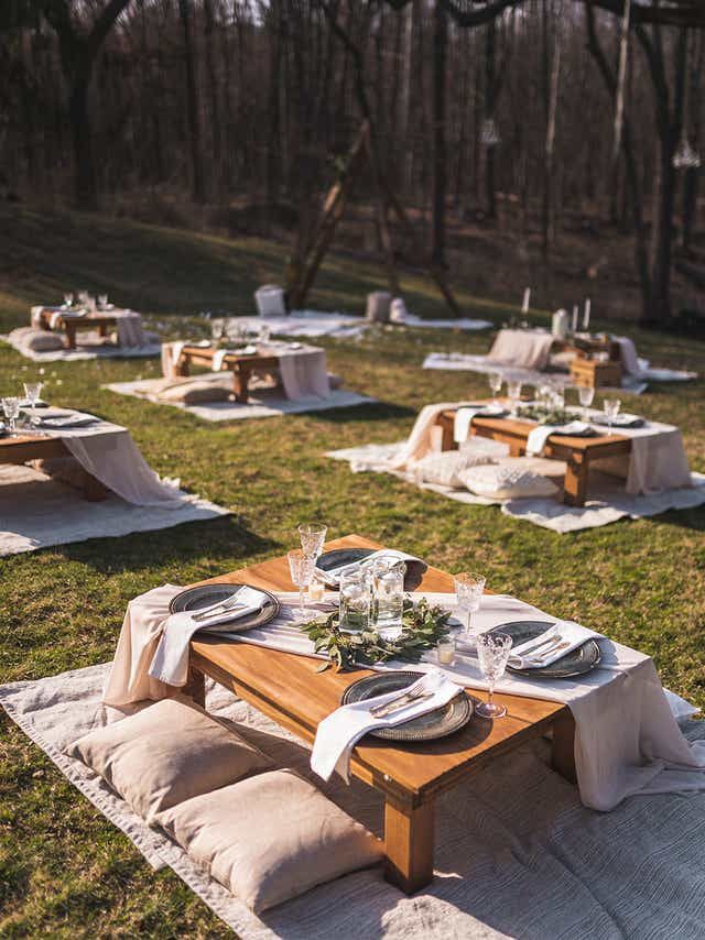 an outdoor table set up with place settings for dinner in the park, ready to be served