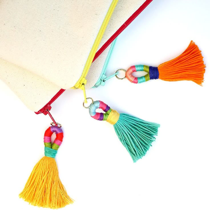 two tassels are attached to a white bag with red string and yellow tassel