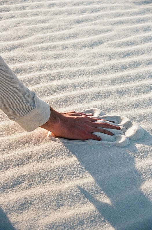 a person standing on top of a white sand covered beach next to a frisbee