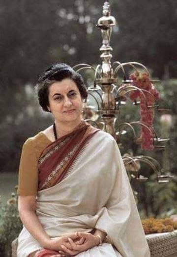 a woman wearing a white sari sitting on a bench