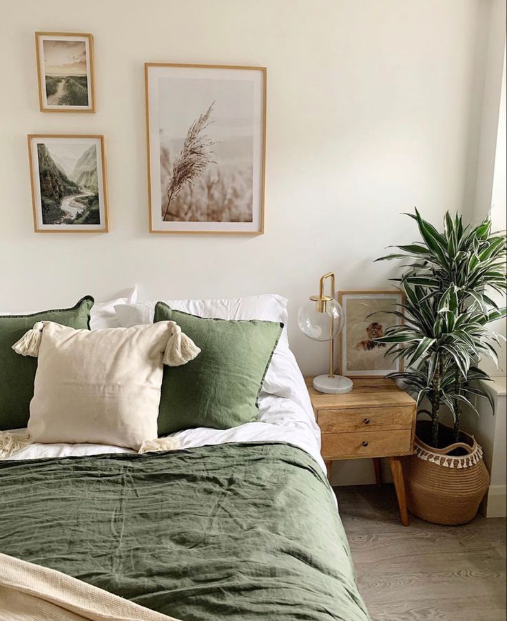 a bed with green linens and pillows in a bedroom next to pictures on the wall