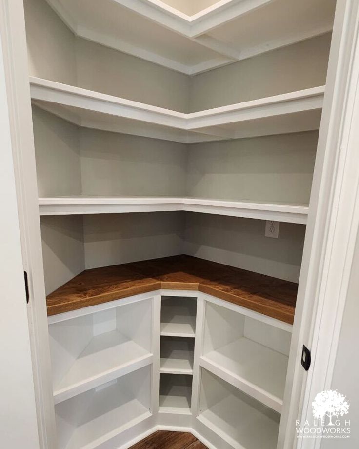 an empty walk in closet with white shelves and wood flooring on the bottom shelf