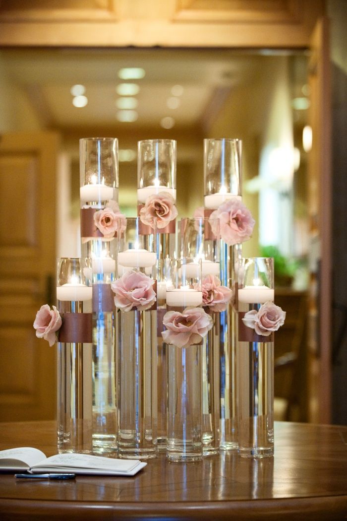 there are many tall vases with flowers in them on the table and one is filled with candles