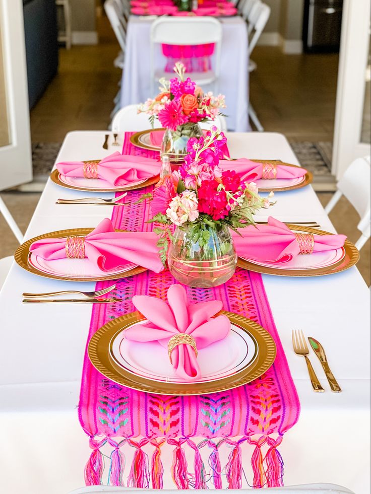 the table is set with pink and gold place settings