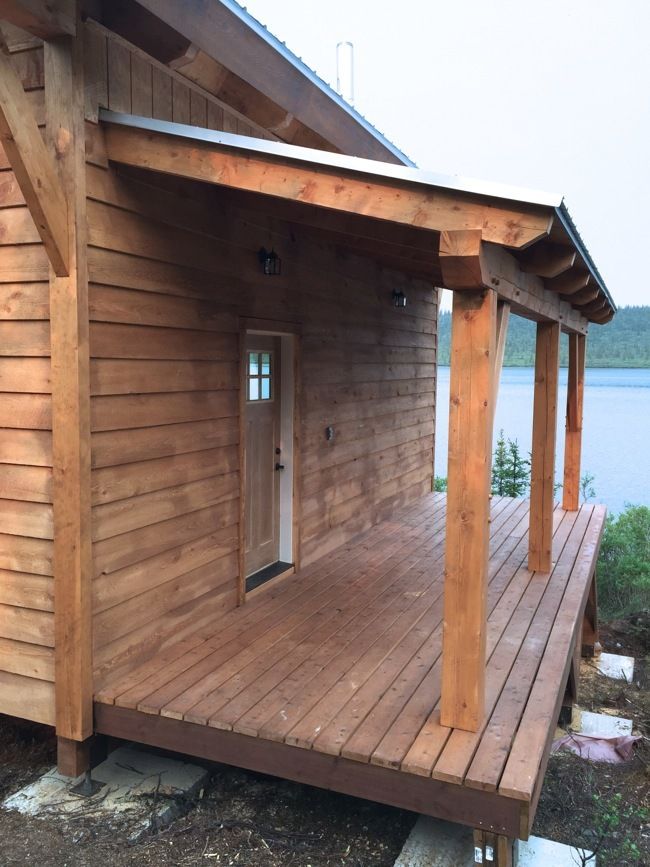 a small wooden house sitting on top of a wooden deck next to a body of water