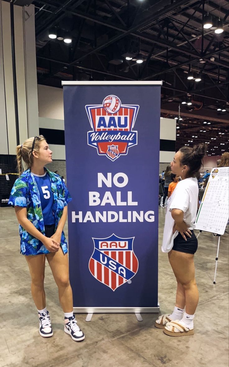 two girls standing next to a sign that says no ball handling in front of them