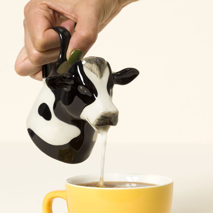 a person pouring milk into a cup with a cow head on it