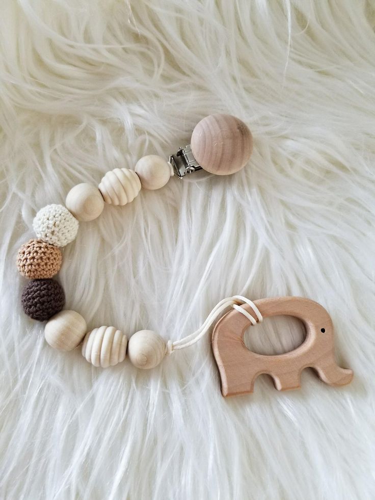 a wooden elephant pacifier is laying on a white fur covered floor next to an elephant toy