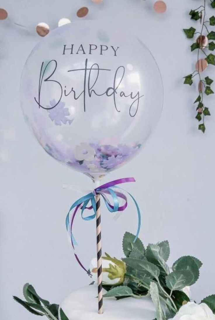 a birthday cake with a balloon on top and greenery around it that says happy birthday