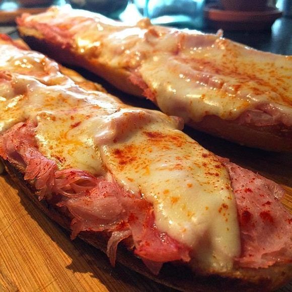 two slices of pizza sitting on top of a wooden cutting board next to each other