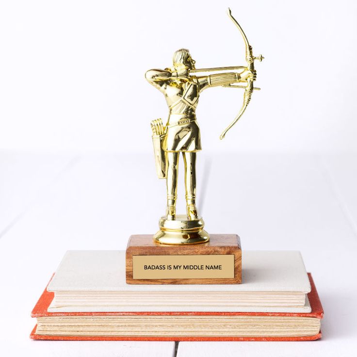 a golden statue holding a bow and arrow on top of two bookends that are stacked next to each other