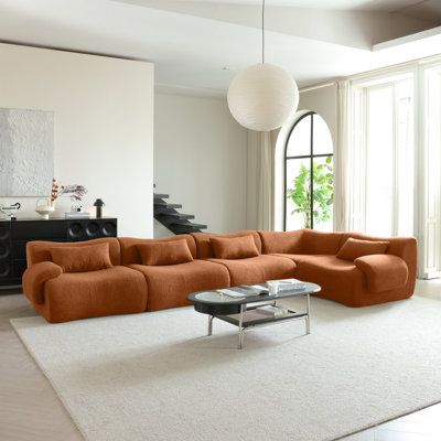 a living room with an orange couch and white rug