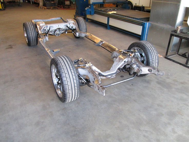 the front wheels and suspensions of a car in a garage with other parts on the floor