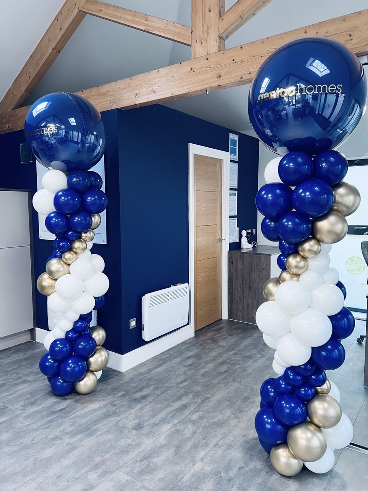 blue and gold balloon columns in the middle of a room with white and gold balloons