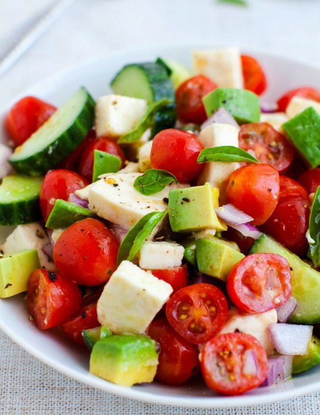 a salad with tomatoes, cucumbers, and other vegetables in it on a white plate