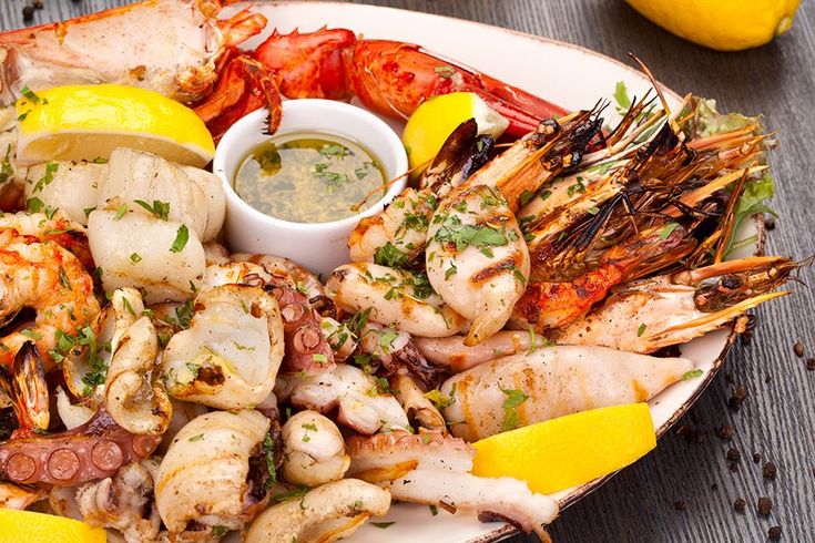 a plate full of seafood with lemon wedges