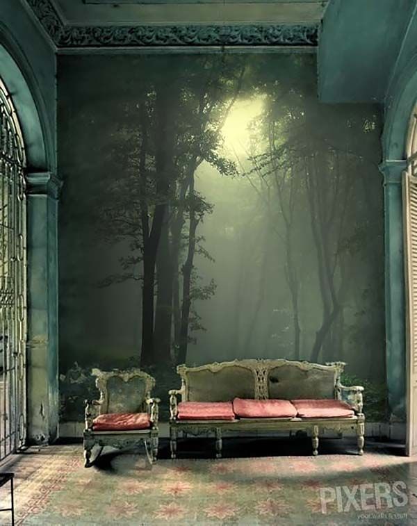 an empty room with a couch in front of a wall mural that has a forest scene on it