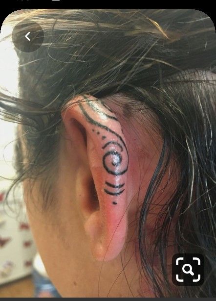 a person with a tattoo on their ear and behind the ear is a small circle