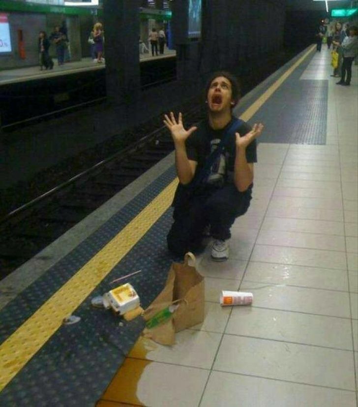 a man sitting on the ground in front of a train station with his hands up