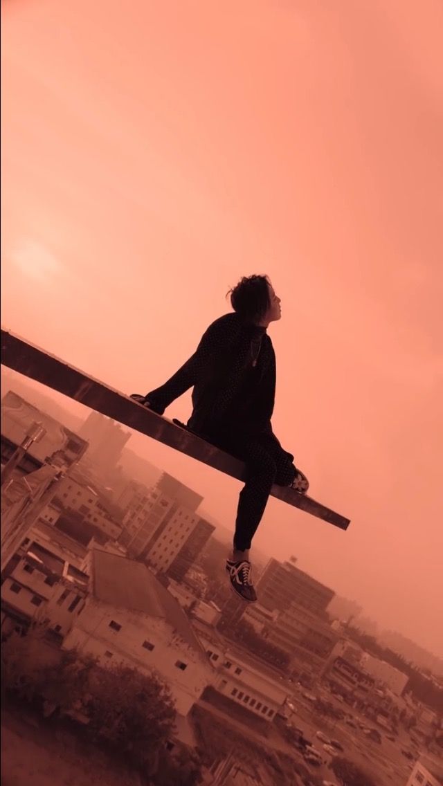 a man sitting on top of a wooden bench in front of a cityscape