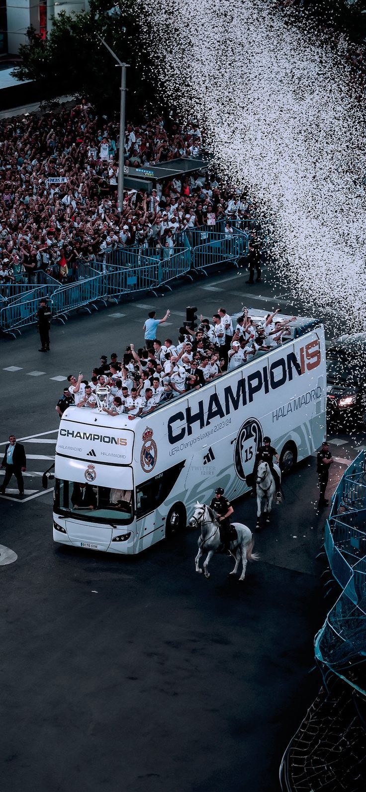 a large group of people standing on top of a white bus in front of a crowd