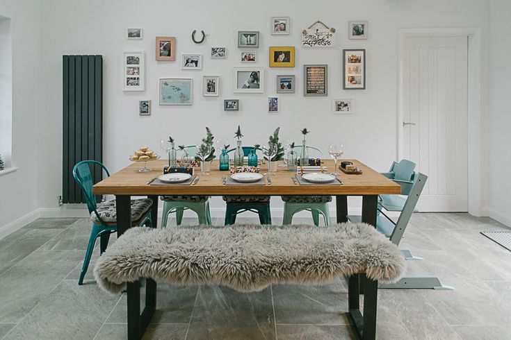 a dining room table set with plates and place settings on the wall above it is a bench