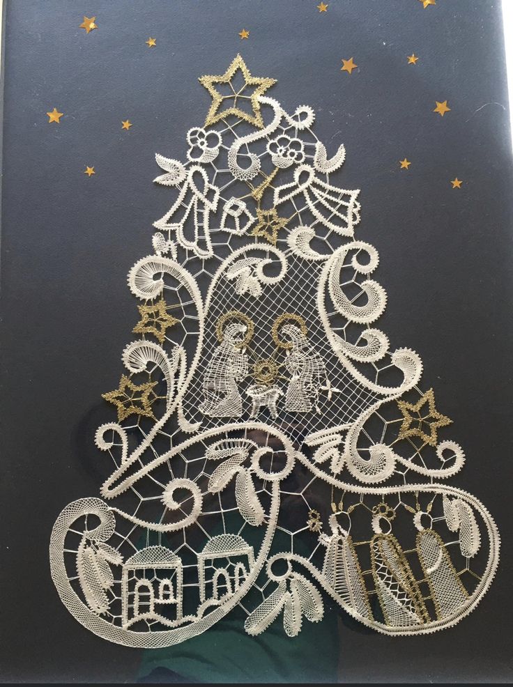 a christmas tree made out of lace on a black board with gold stars and snowflakes