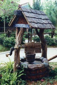 a wooden water well in the middle of a garden