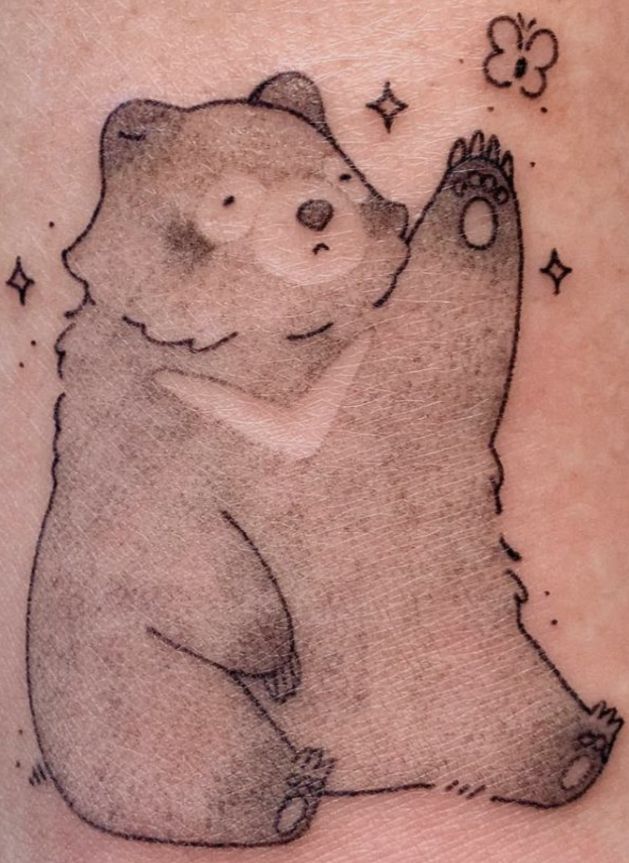 a drawing of a bear on the back of a woman's leg with stars around it