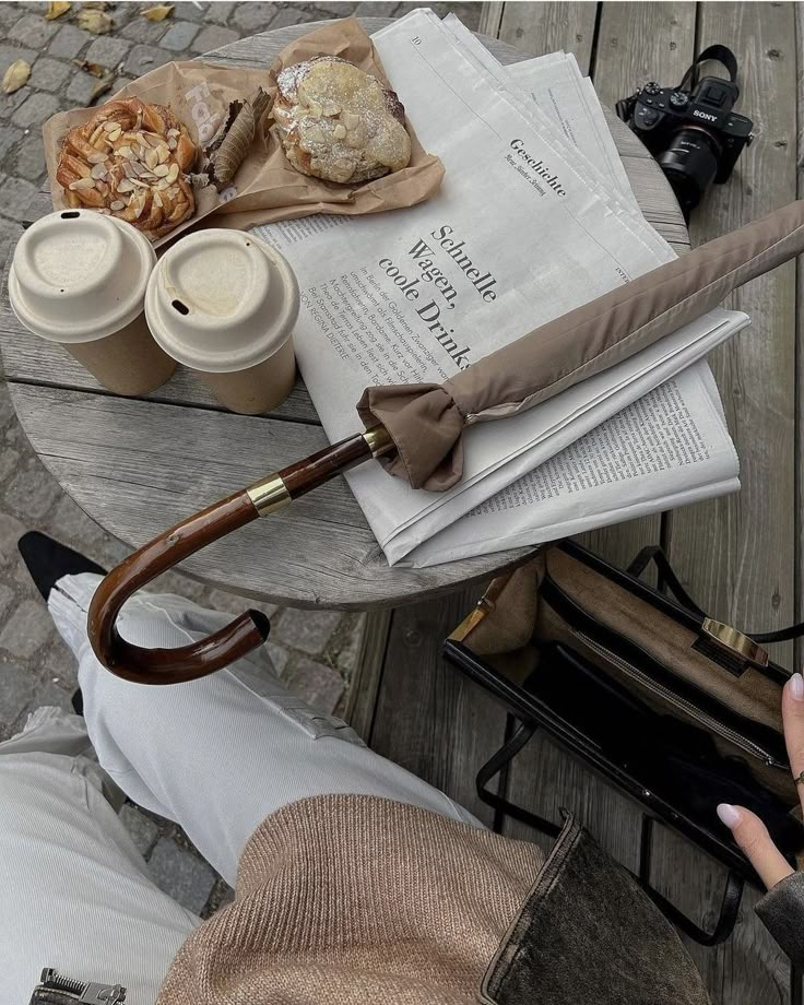 a table with an umbrella and some food on it next to a woman's purse