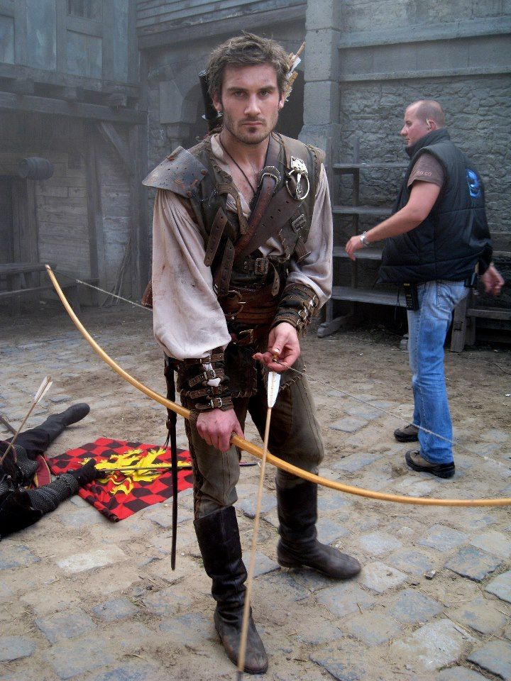 a man dressed in medieval clothing holding a bow